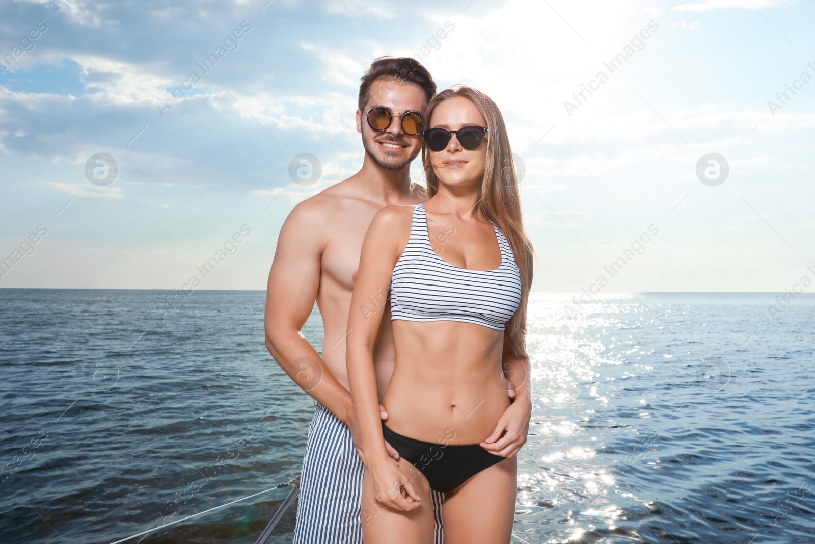 Photo of Young man and his beautiful girlfriend in bikini on yacht. Happy couple on vacation