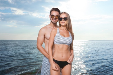 Young man and his beautiful girlfriend in bikini on yacht. Happy couple on vacation