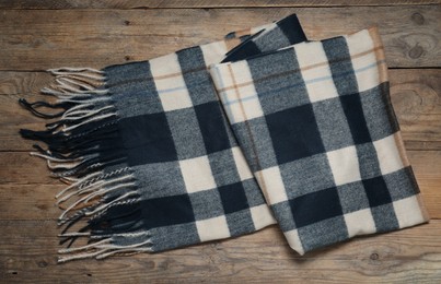 Photo of Soft checkered scarf on wooden table, top view