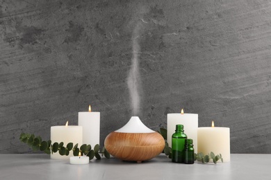 Photo of Composition with essential oils diffuser on table against grey background. Space for text