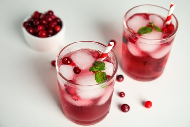 Photo of Tasty refreshing cranberry cocktail with mint on white table