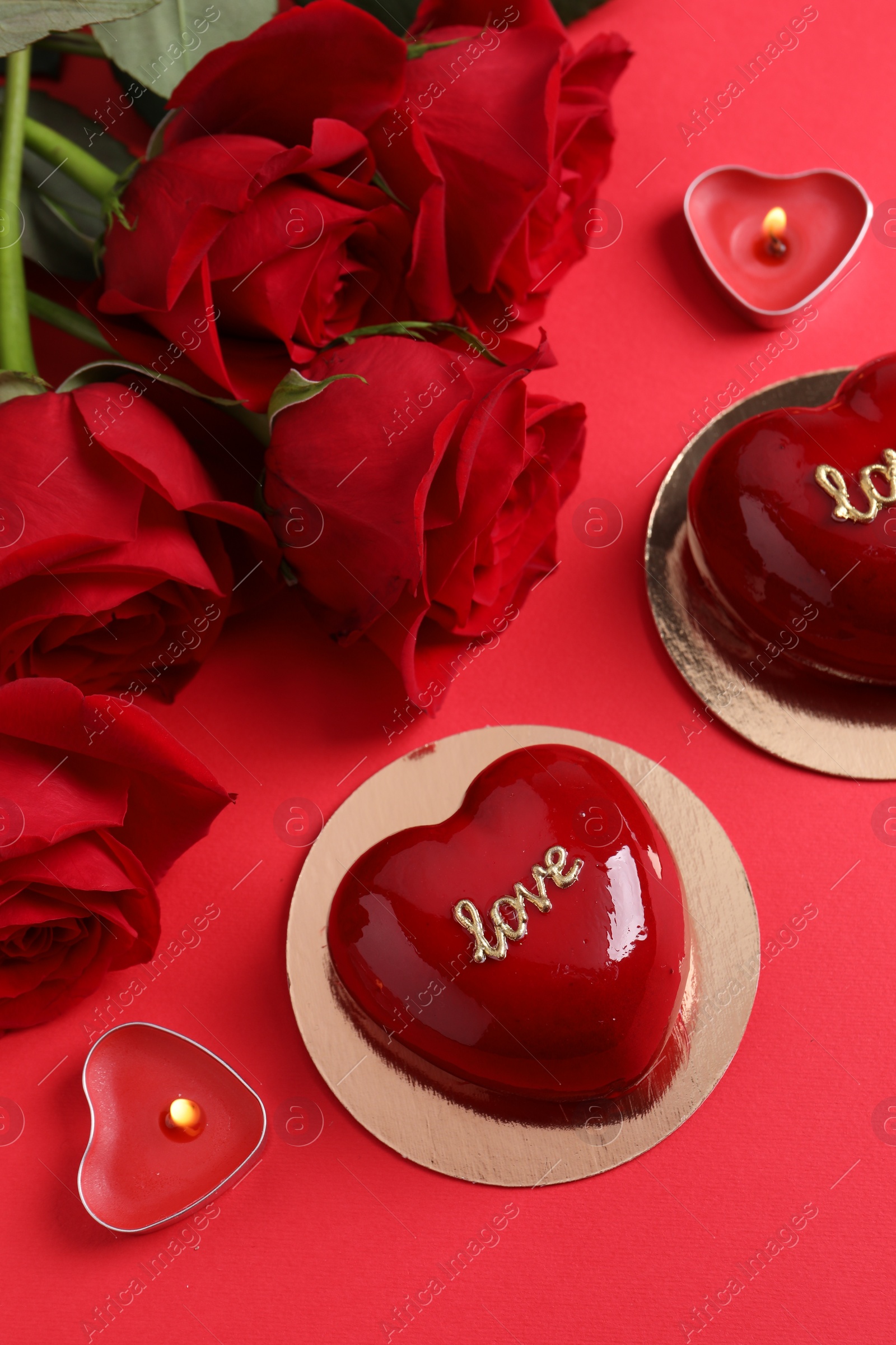 Photo of St. Valentine's Day. Delicious heart shaped cakes and roses on red background, flat lay