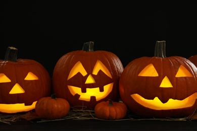 Glowing jack o'lanterns on table in darkness. Halloween decor