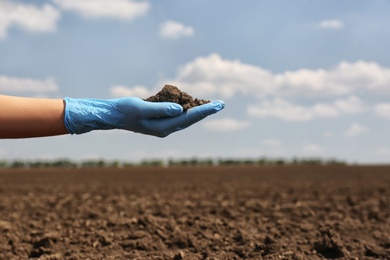 Woman holding pile of soil outdoors, closeup. Space for text