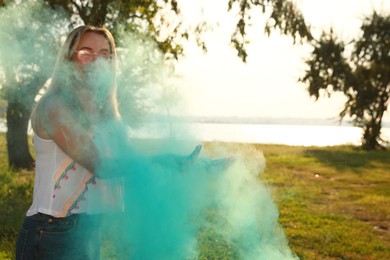 Happy woman with blue powder dye outdoors, space for text. Holi festival celebration