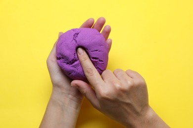 Photo of Woman playing with kinetic sand on yellow background, top view