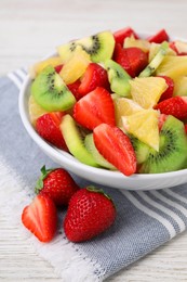 Photo of Delicious fresh fruit salad in bowl on white wooden table, closeup