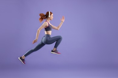 Photo of Woman in sportswear jumping on violet background, space for text