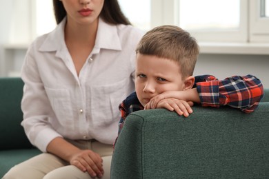 Psychologist working with unhappy little boy in office. Mental health problems