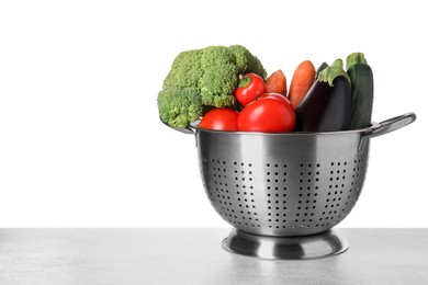 Different fresh vegetables in colander on table against white background. Space for text