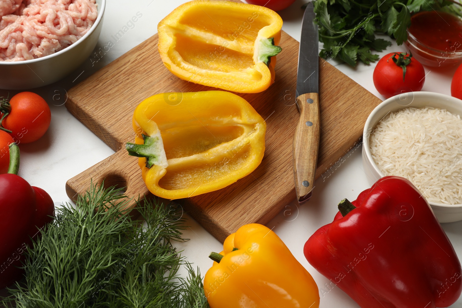 Photo of Raw stuffed peppers with ground meat and ingredients on white marble table, above view