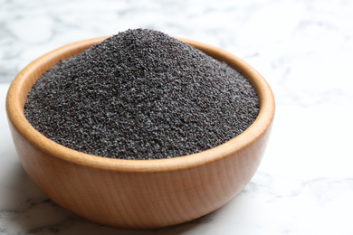 Poppy seeds in bowl on white marble table