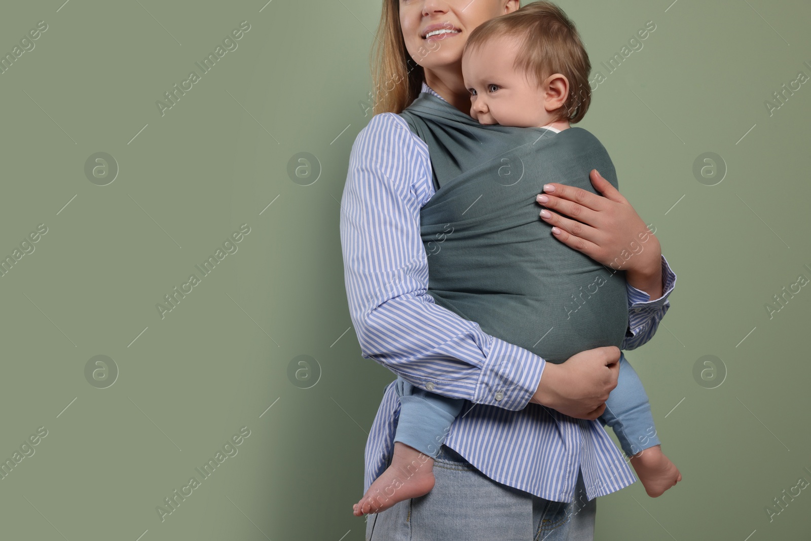 Photo of Mother holding her child in baby wrap on olive background, closeup. Space for text