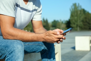 Photo of Man using modern mobile phone outdoors, closeup