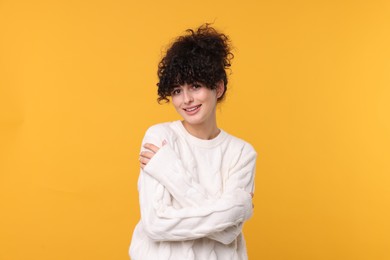 Photo of Happy young woman in stylish white sweater on yellow background