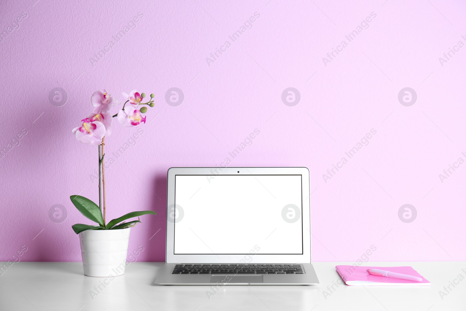 Photo of Modern laptop monitor on table against color wall. Mock up with space for text
