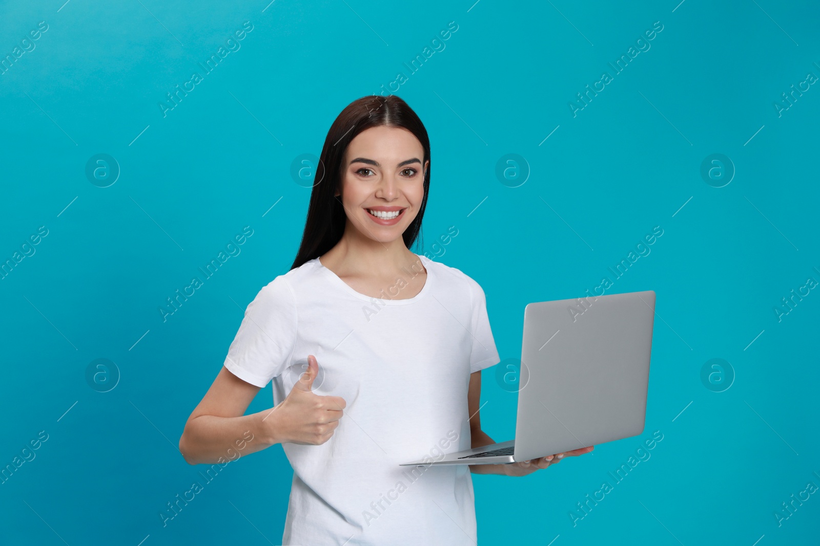 Photo of Young woman with modern laptop on light blue background