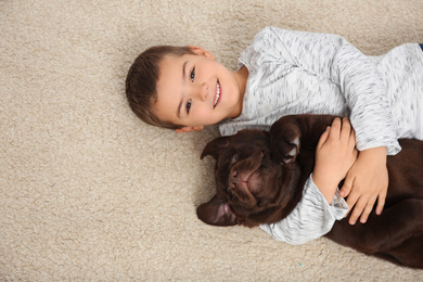 Photo of Little boy with dog lying on floor, top view