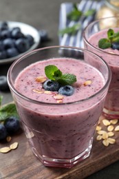 Photo of Glass of tasty blueberry smoothie with oatmeal on wooden board, closeup