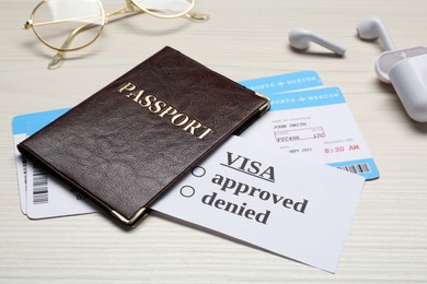 Photo of Passport, tickets, earphones and glasses on white wooden table, closeup. Visa receiving