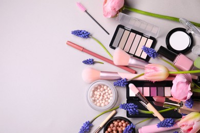 Photo of Flat lay composition with different makeup products and beautiful spring flowers on gray background, space for text