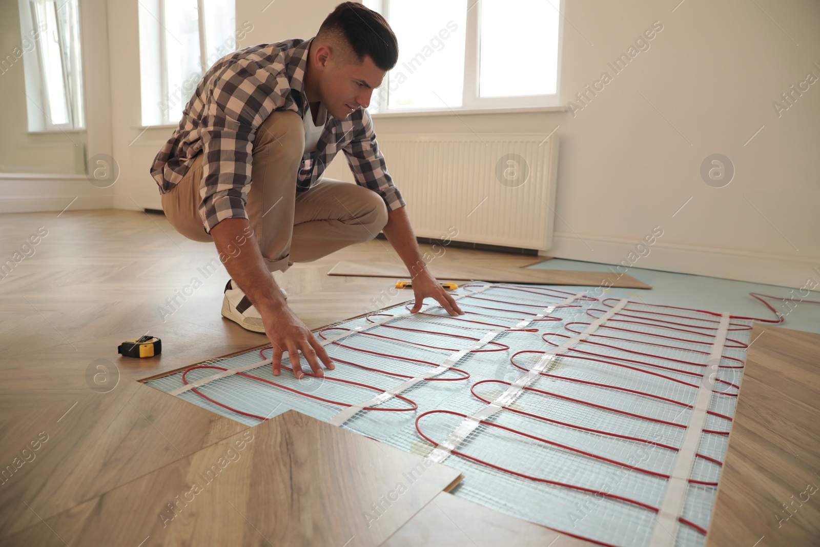 Photo of Professional worker installing electric underfloor heating system indoors