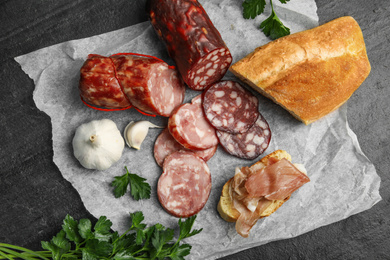 Photo of Different types of sausages and bread on black table, flat lay