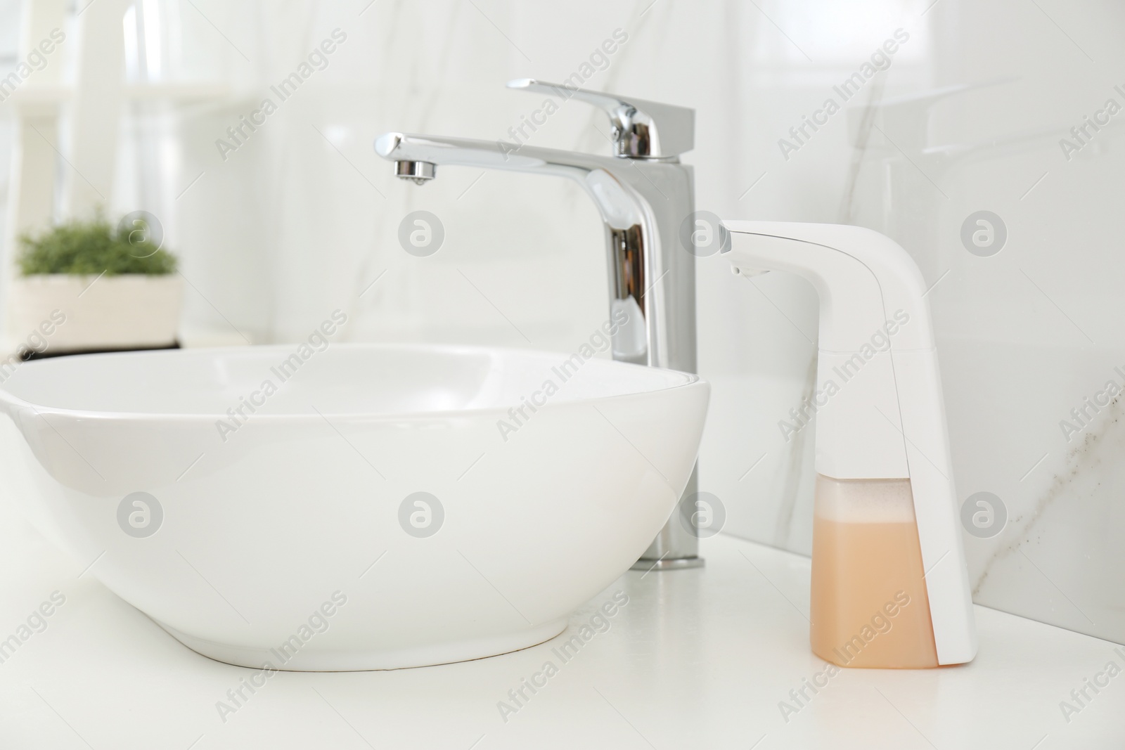 Photo of Modern automatic soap dispenser near sink in bathroom, closeup