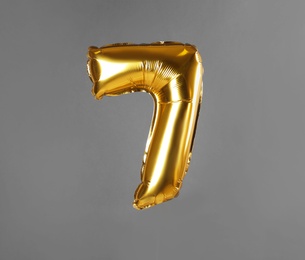 Golden number seven balloon on grey background