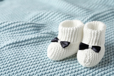 Photo of Handmade baby booties on soft plaid. Space for text