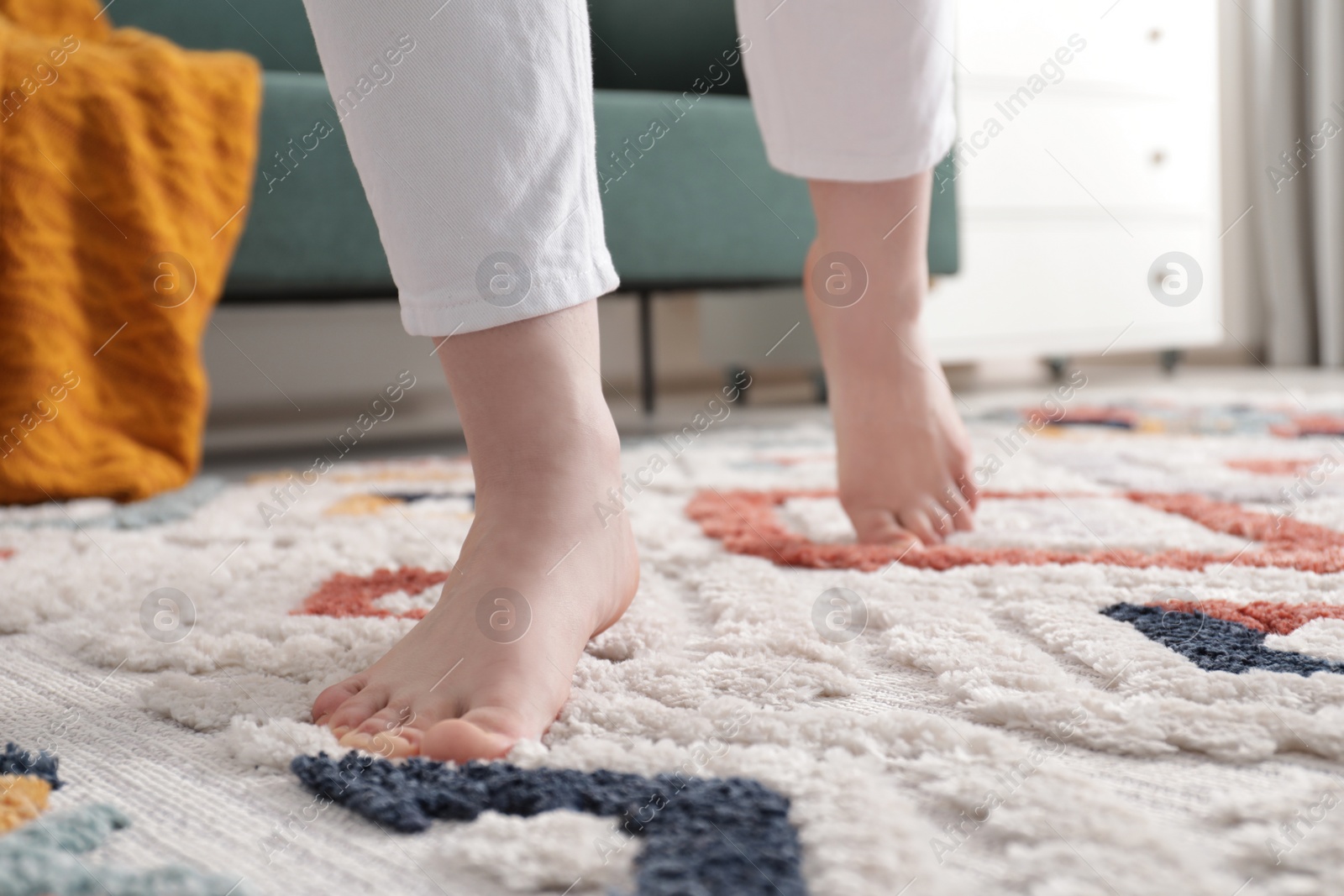 Photo of Woman standing on carpet with pattern at home, closeup