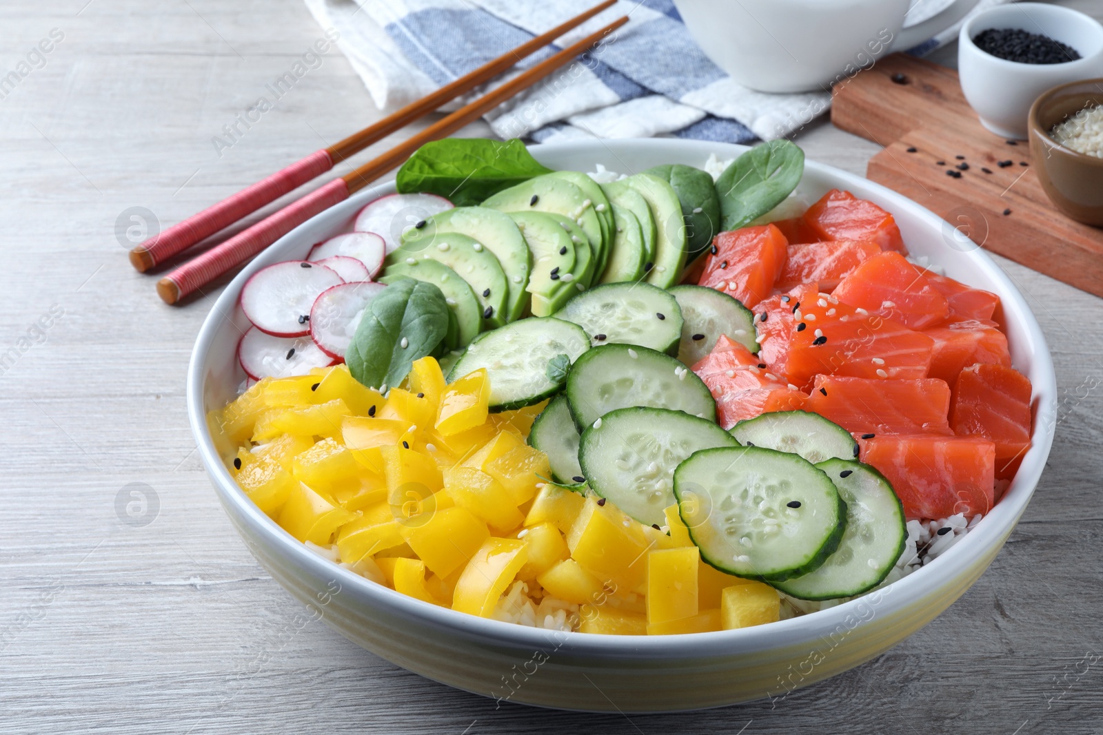 Photo of Delicious poke bowl with salmon and vegetables served on wooden table, closeup