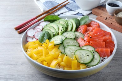 Delicious poke bowl with salmon and vegetables served on wooden table, closeup
