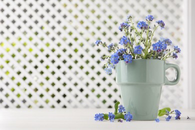 Photo of Beautiful blue forget-me-not flowers on white wooden table. Space for text