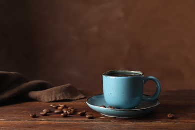 Photo of Turkish coffee. Freshly brewed beverage and beans on wooden table against brown background, space for text