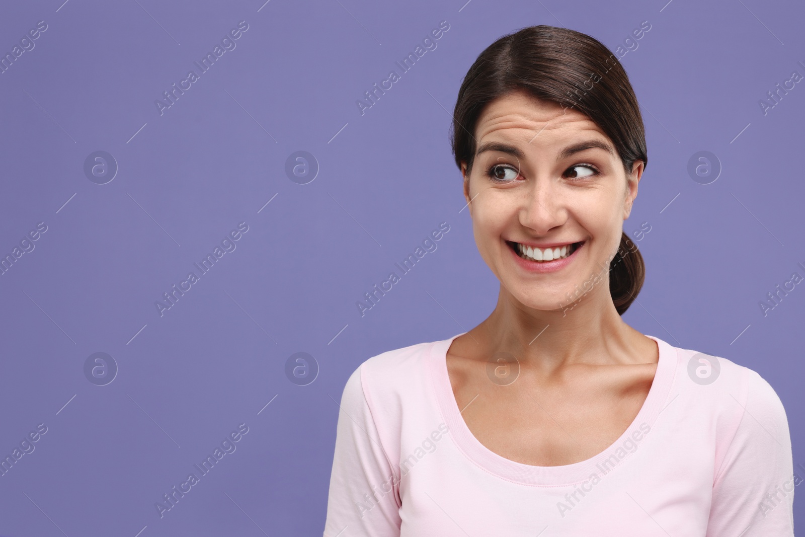 Photo of Portrait of embarrassed young woman on violet background, space for text