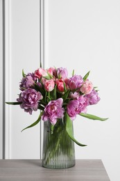 Photo of Beautiful bouquet of colorful tulip flowers in vase on wooden table