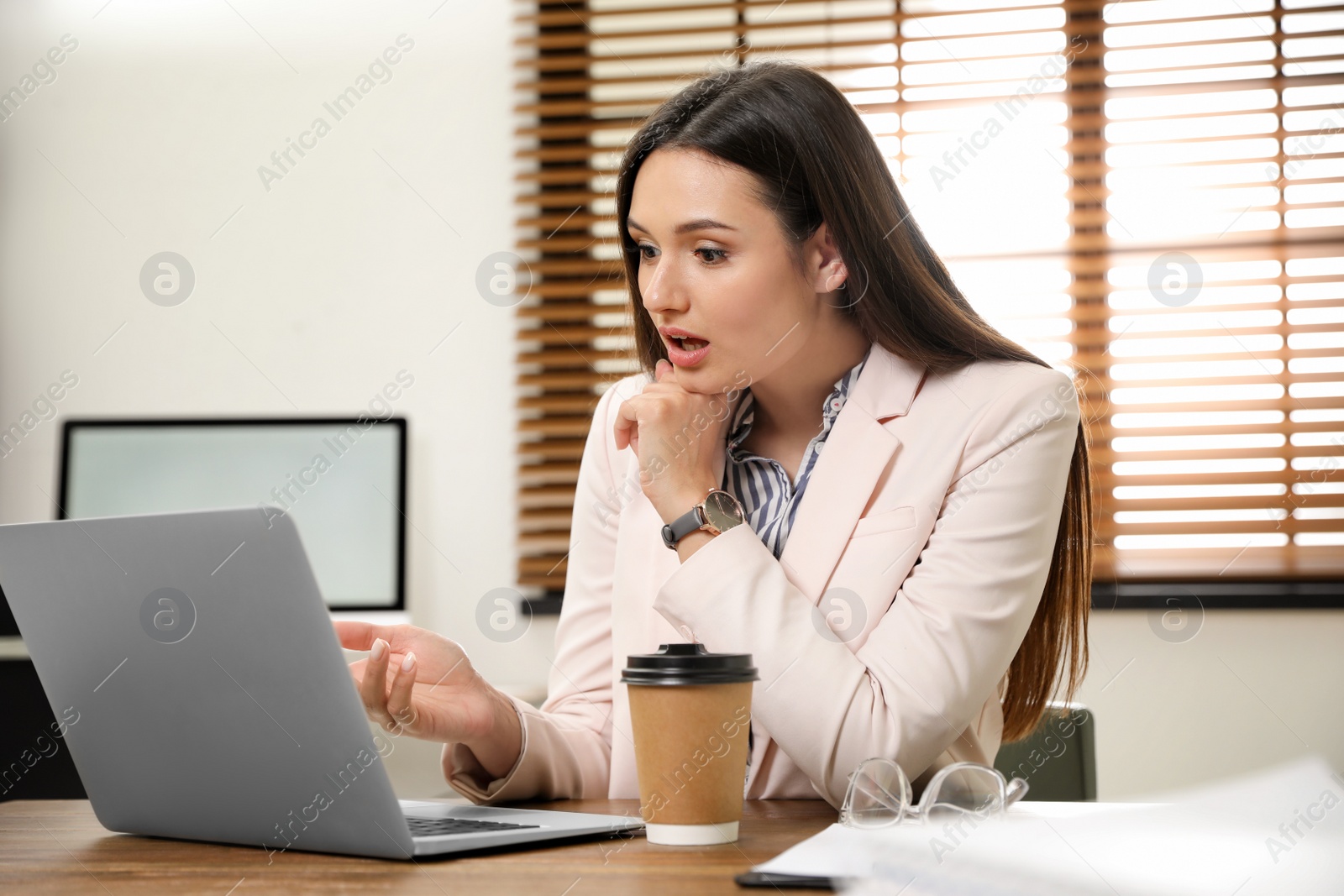 Photo of Young woman using video chat on laptop in home office