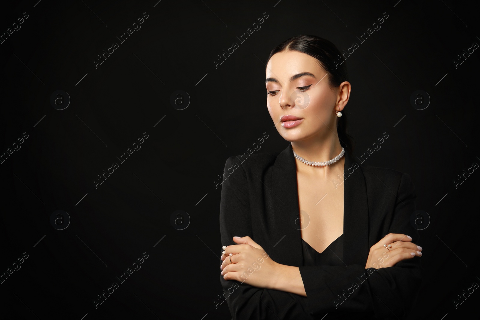 Photo of Young woman with elegant pearl jewelry on black background, space for text