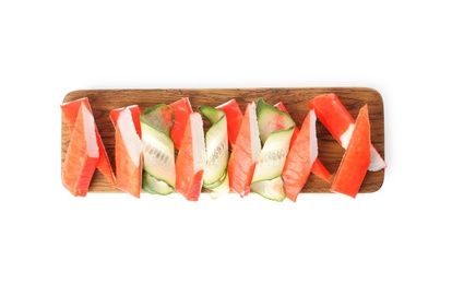 Wooden board with crab sticks and cucumber on white background, top view