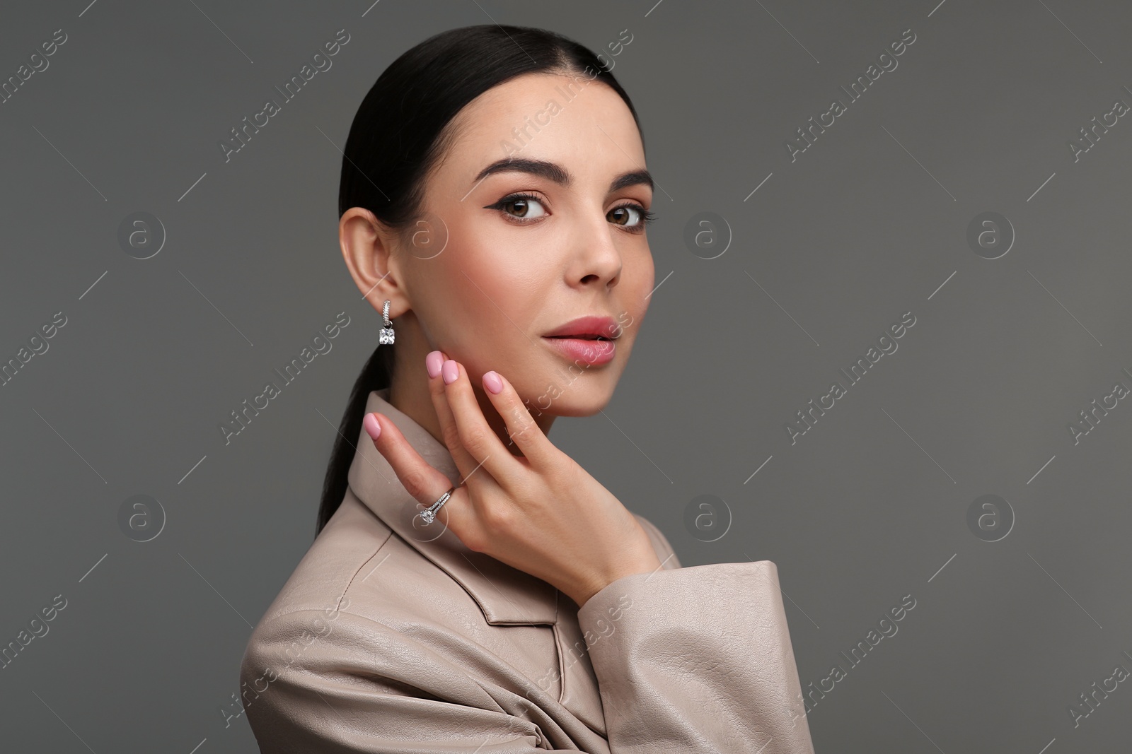 Photo of Beautiful young woman with elegant jewelry on dark grey background