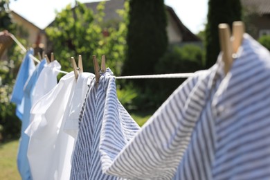 Photo of Clean clothes hanging on washing line in garden, closeup. Drying laundry