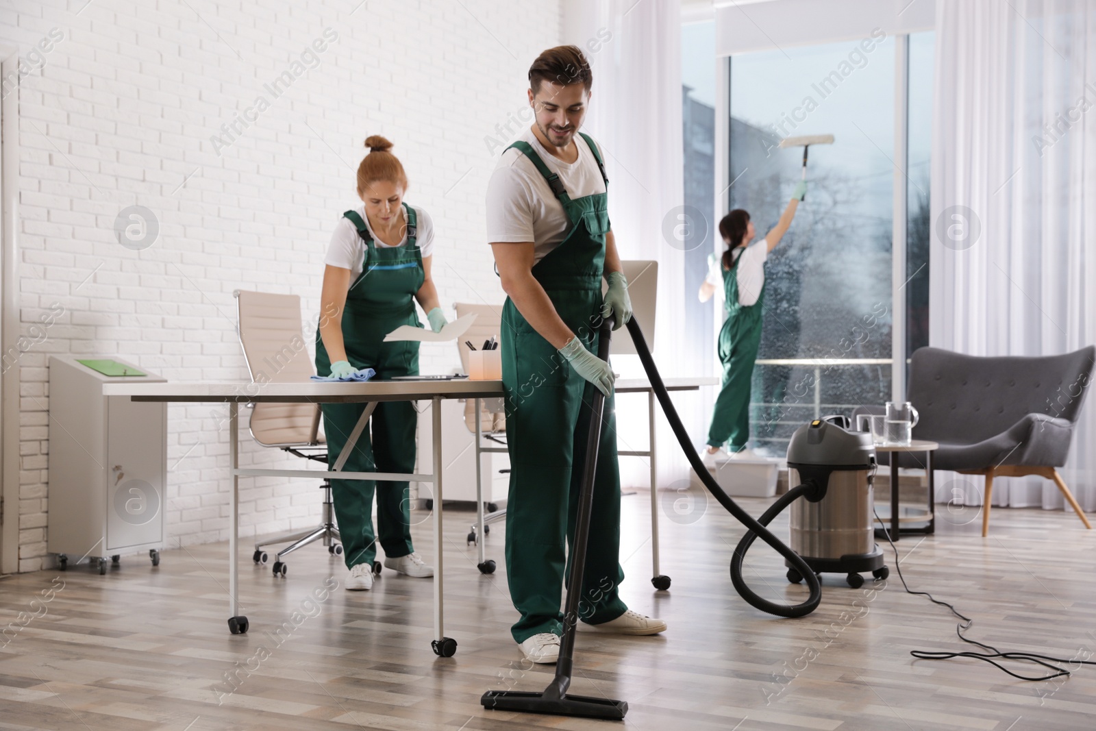 Photo of Team of professional janitors working in modern office. Cleaning service