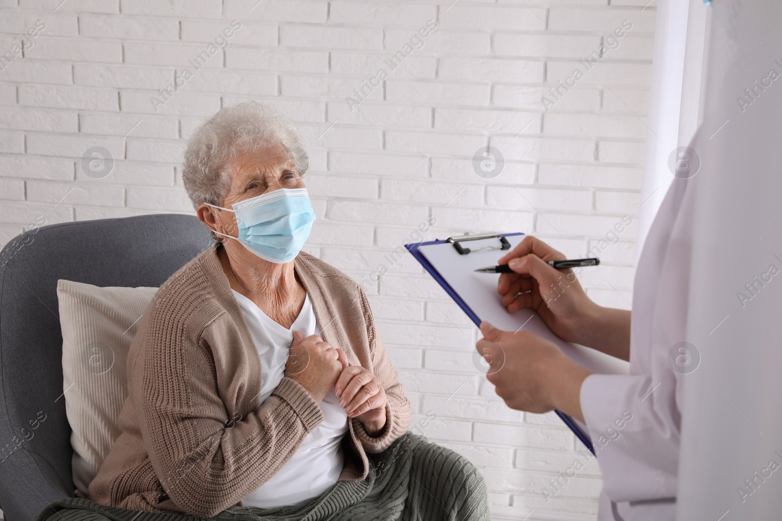 Photo of Doctor examining senior woman with protective mask at nursing home