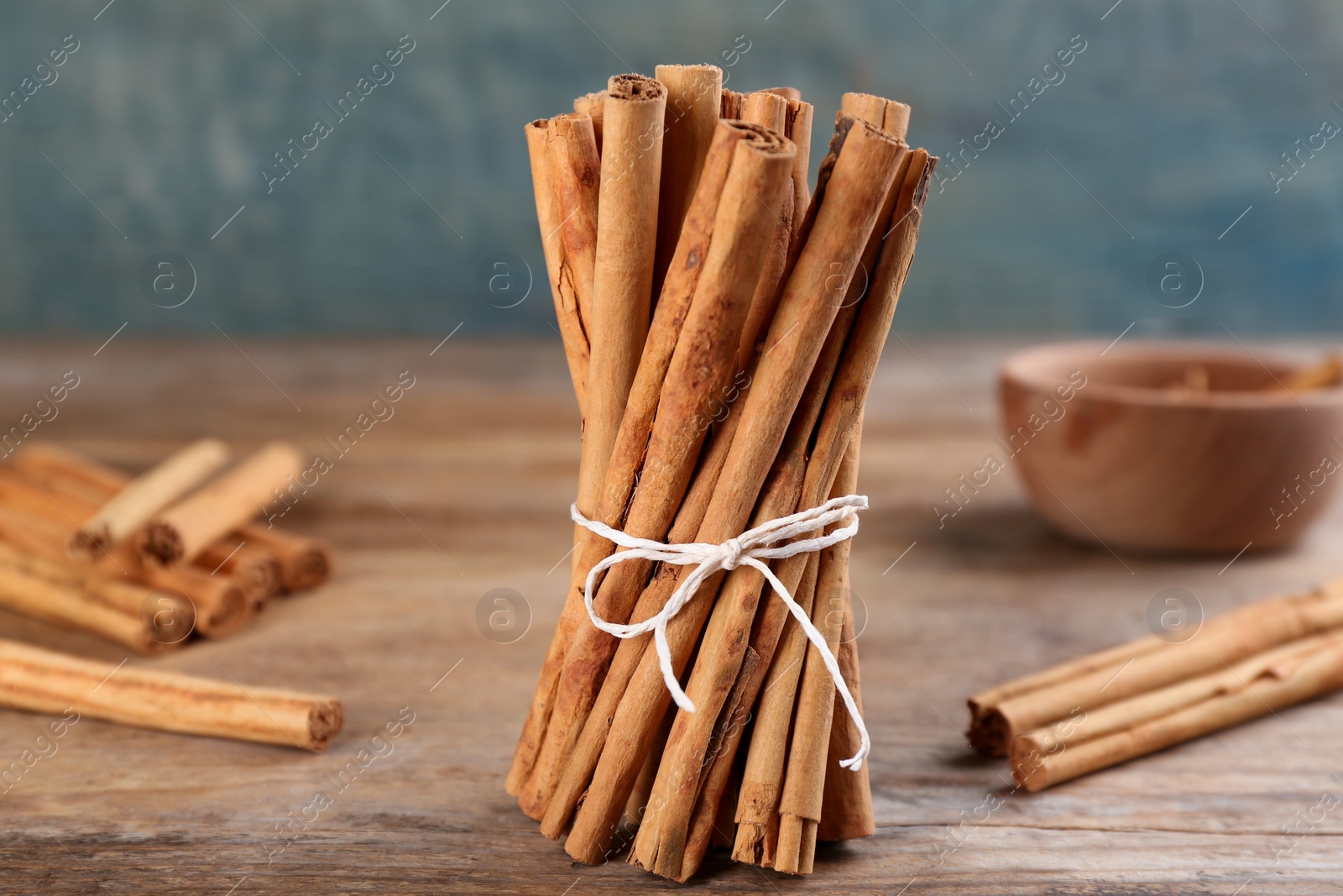 Photo of Ties aromatic cinnamon sticks on wooden table