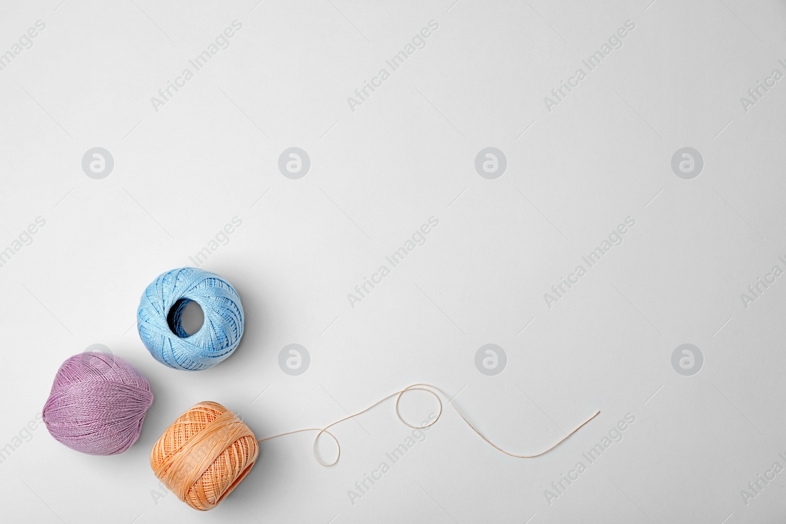 Photo of Color sewing threads on white background, top view