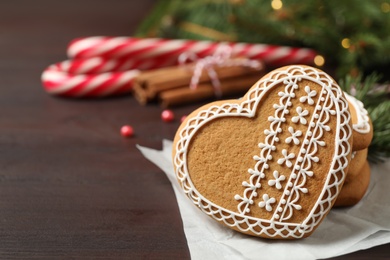 Tasty heart shaped gingerbread cookies and Christmas decor on wooden table, closeup. Space for text