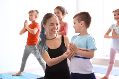 Photo of Little children and their teacher practicing yoga in gym