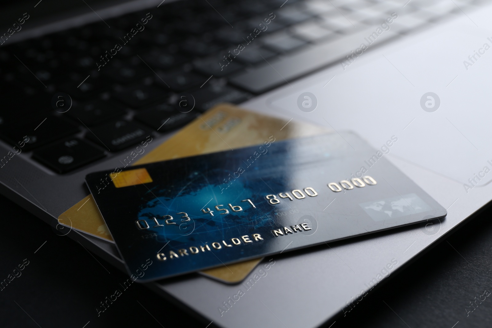 Photo of Laptop with credit cards on dark table, closeup