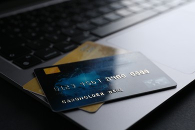 Photo of Laptop with credit cards on dark table, closeup